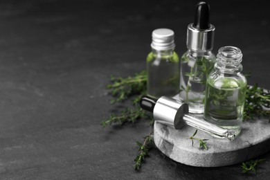Photo of Thyme essential oil on black table, space for text