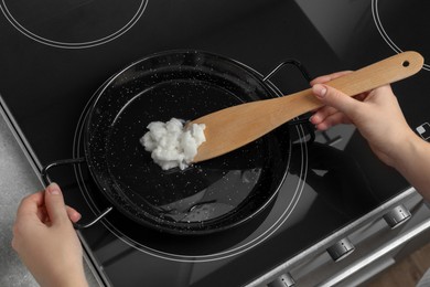 Woman cooking with coconut oil on induction stove, closeup