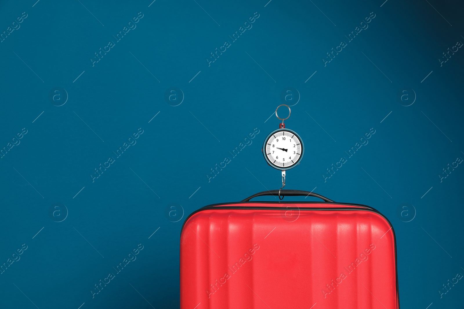 Photo of Modern suitcase and hanging scales against color background, space for text