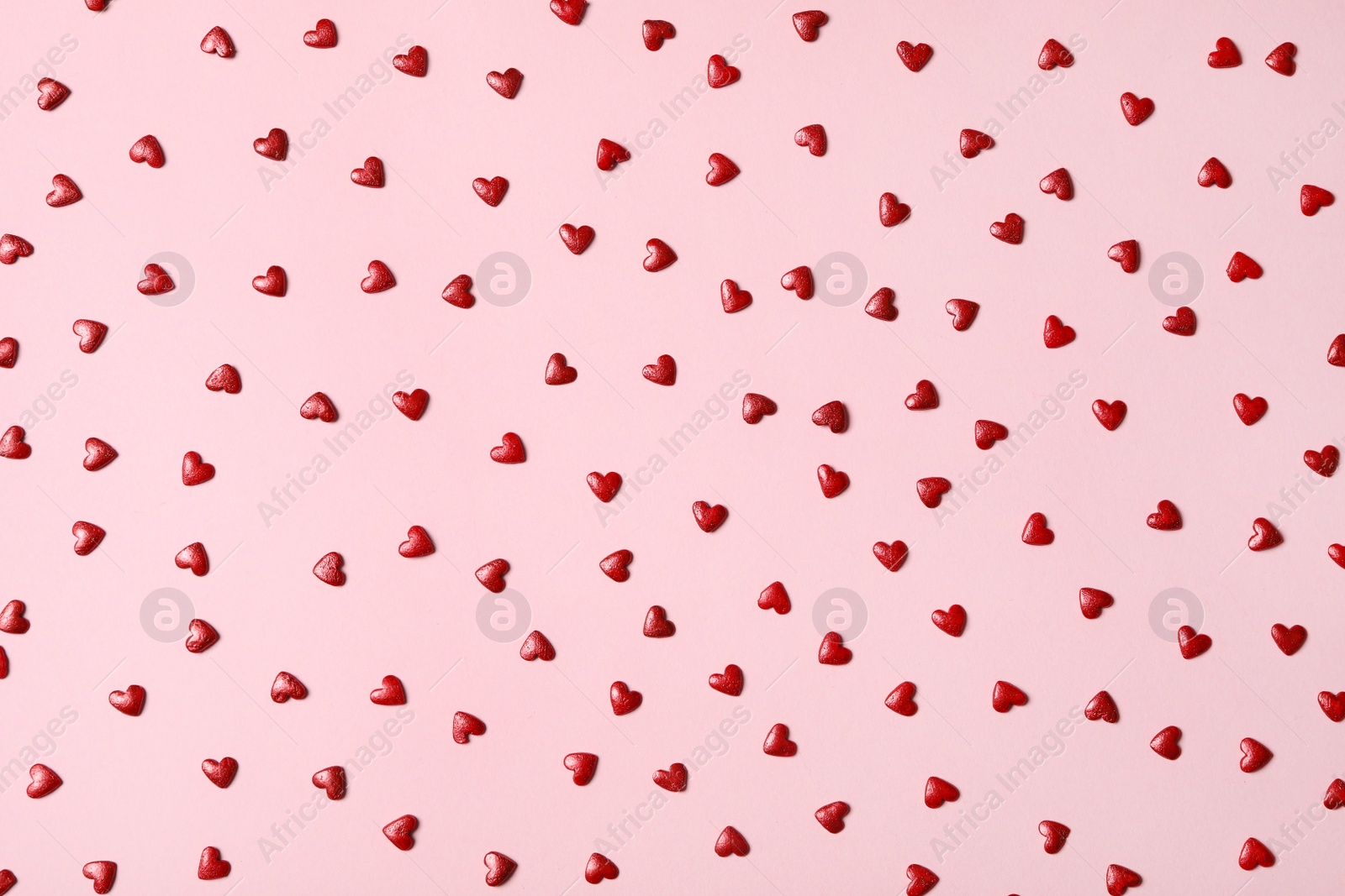 Photo of Red heart shaped sprinkles on pink background, flat lay