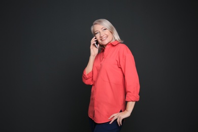 Mature woman talking on mobile phone against black background