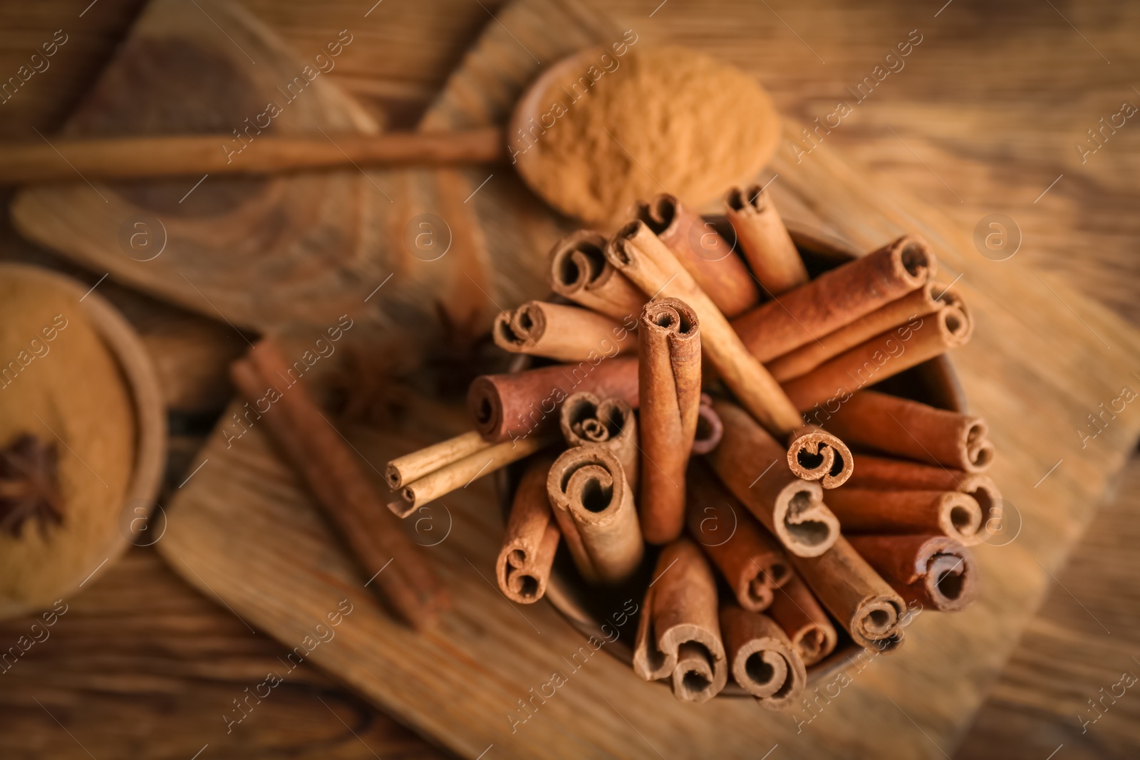 Photo of Bowl with aromatic cinnamon sticks on wooden background