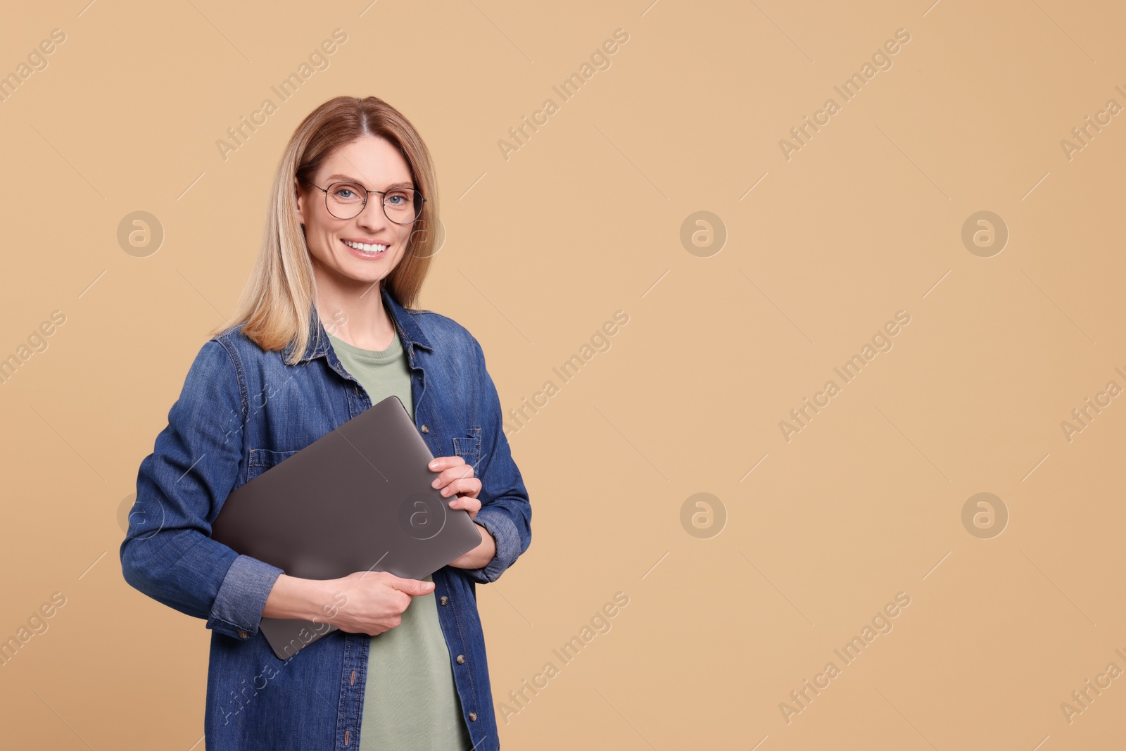 Photo of Happy woman with laptop on beige background. Space for text