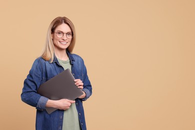 Happy woman with laptop on beige background. Space for text