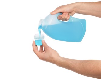 Man pouring fabric softener from bottle into cap for washing clothes on white background, closeup