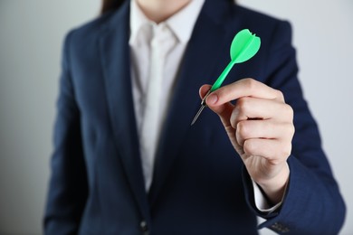 Photo of Businesswoman holding green dart on light background, closeup