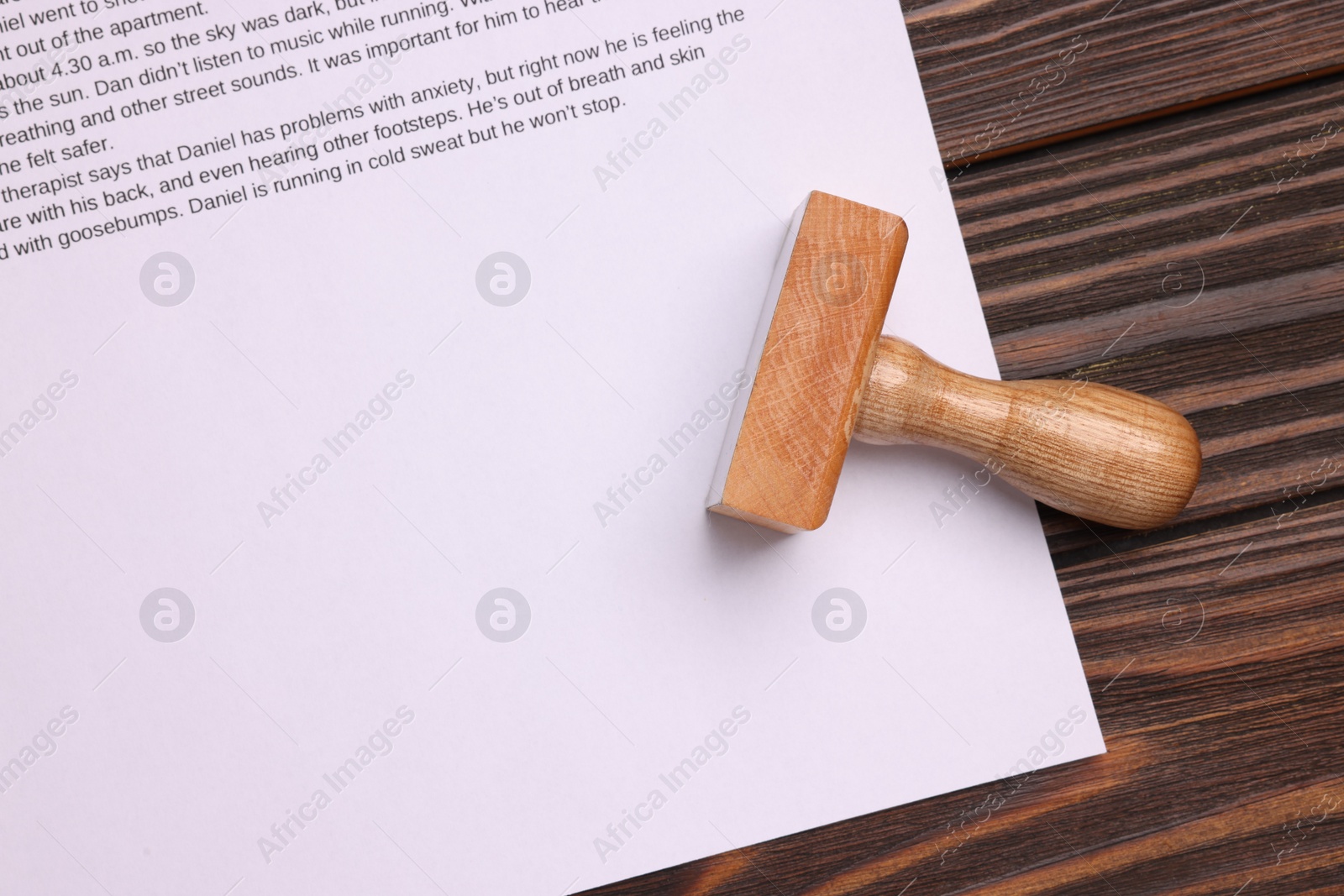 Photo of One stamp tool and document on wooden table, top view