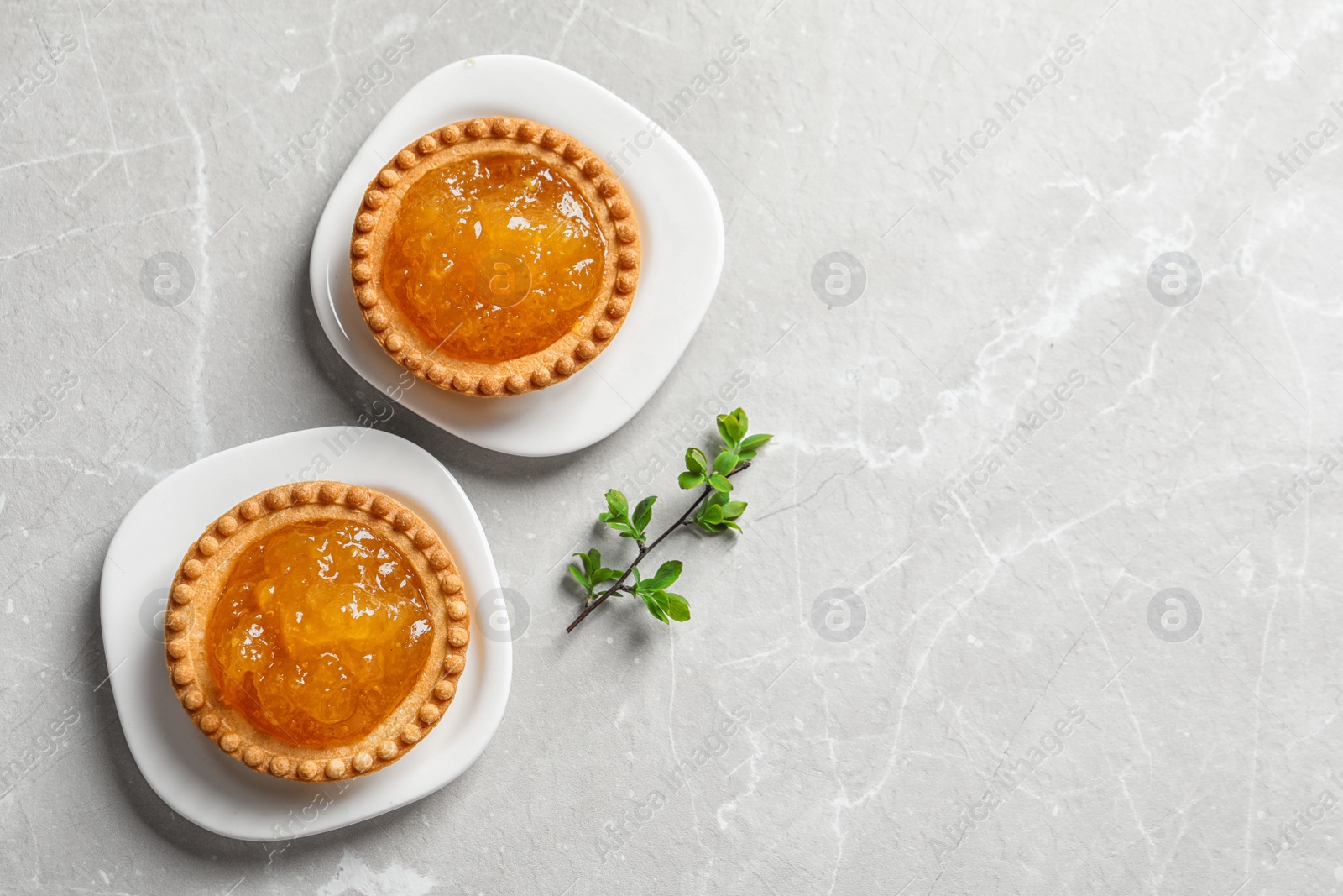 Photo of Tasty tartlets with jam on light background, top view