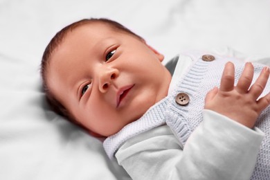 Photo of Newborn baby lying on white blanket, closeup