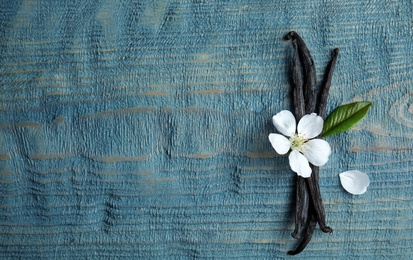 Photo of Flat lay composition with aromatic vanilla sticks and flower on wooden background, space for text