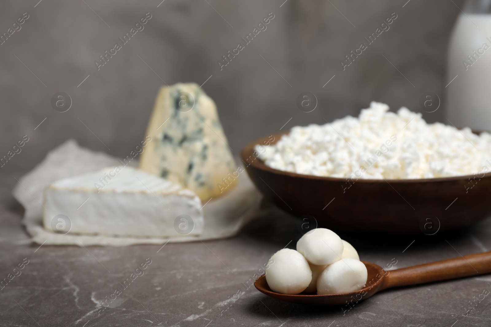 Photo of Spoon with fresh mozzarella balls on table. Dairy products