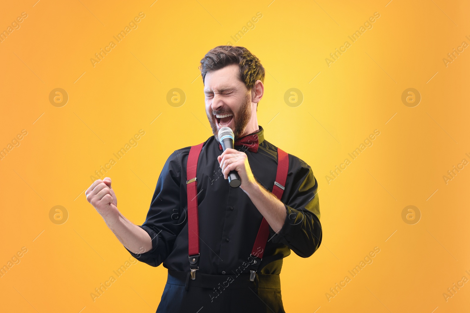 Photo of Emotional man with microphone singing on yellow background