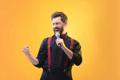 Photo of Emotional man with microphone singing on yellow background