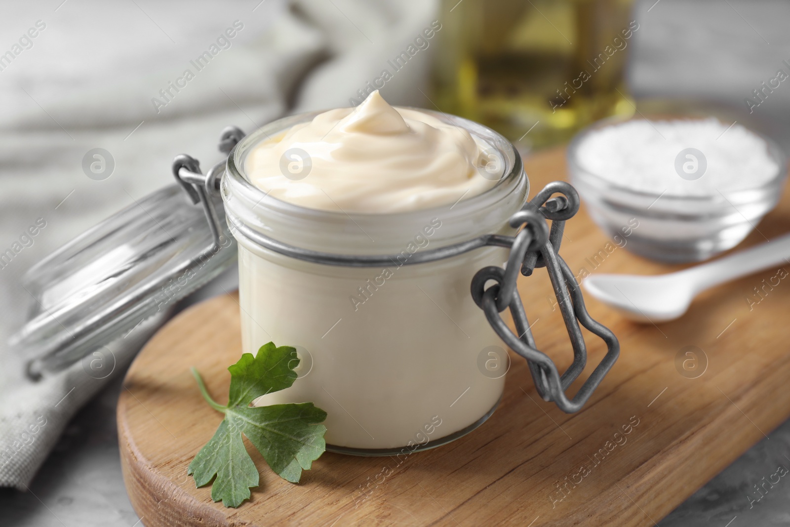 Photo of Tasty mayonnaise in jar and parsley on table, closeup