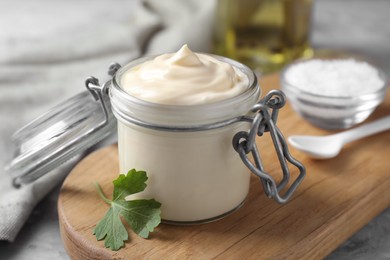 Photo of Tasty mayonnaise in jar and parsley on table, closeup