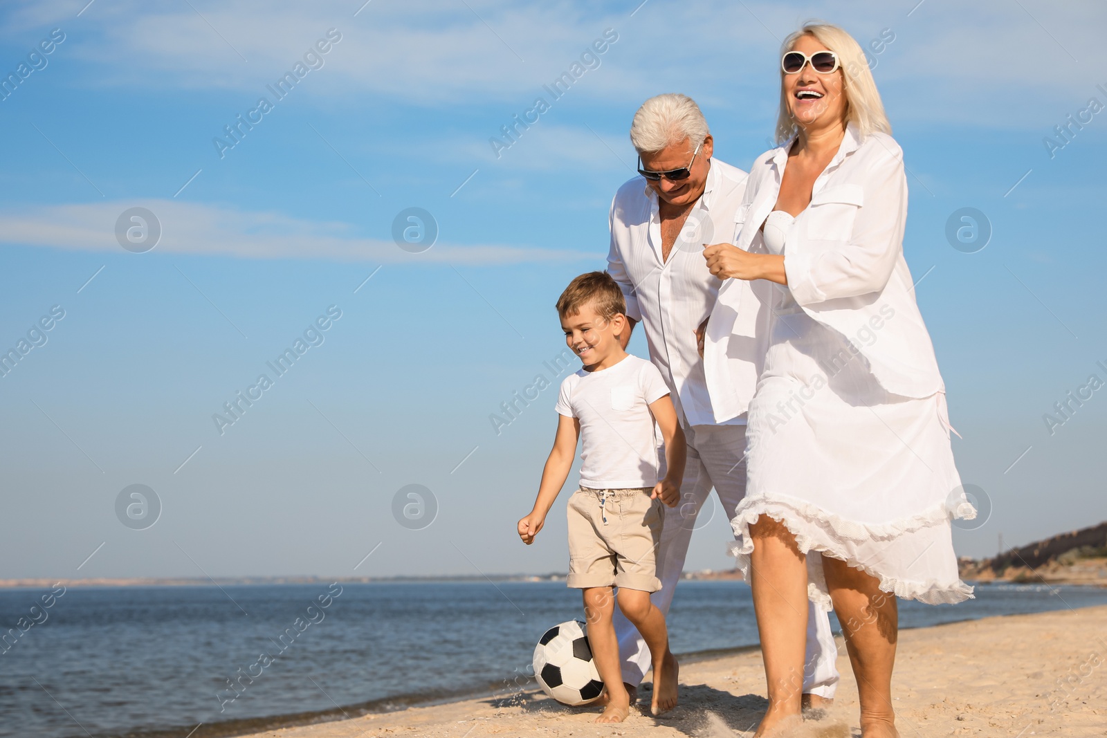 Photo of Cute little boy with grandparents spending time together on sea beach