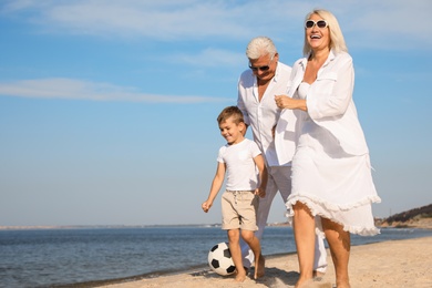 Cute little boy with grandparents spending time together on sea beach