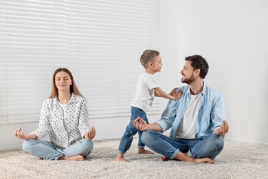 Parents meditating while son distracting them at home