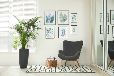 Beautiful paintings of tropical leaves on white wall in room interior