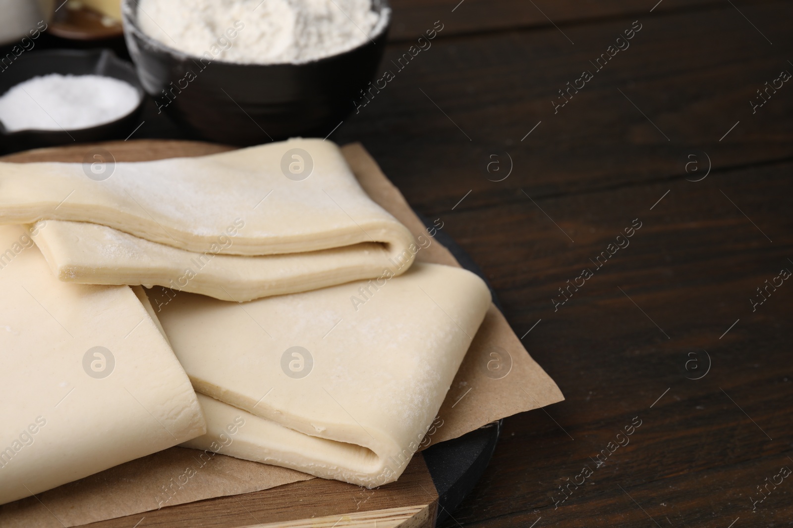 Photo of Raw puff pastry dough on wooden table, closeup. Space for text