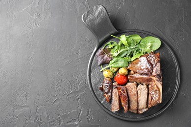 Photo of Delicious grilled beef meat, vegetables and greens on black table, top view. Space for text