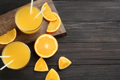 Photo of Delicious orange juice and fresh fruit on black wooden table, flat lay. Space for text