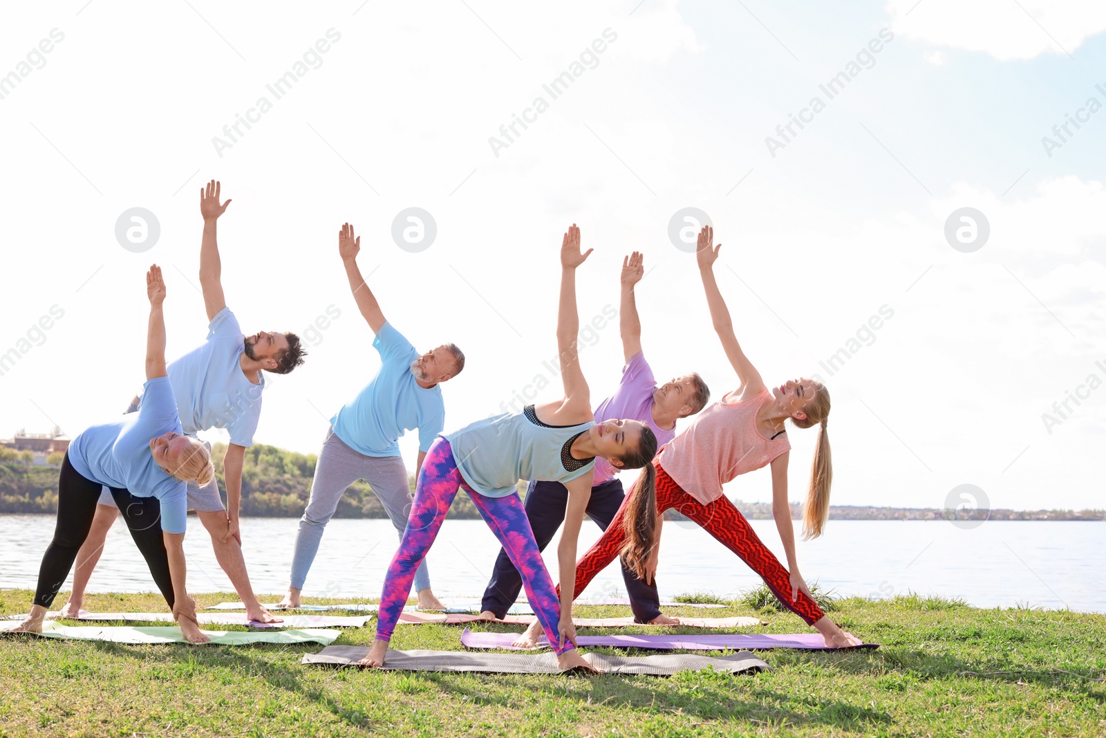 Photo of Group of people practicing yoga near river on sunny day