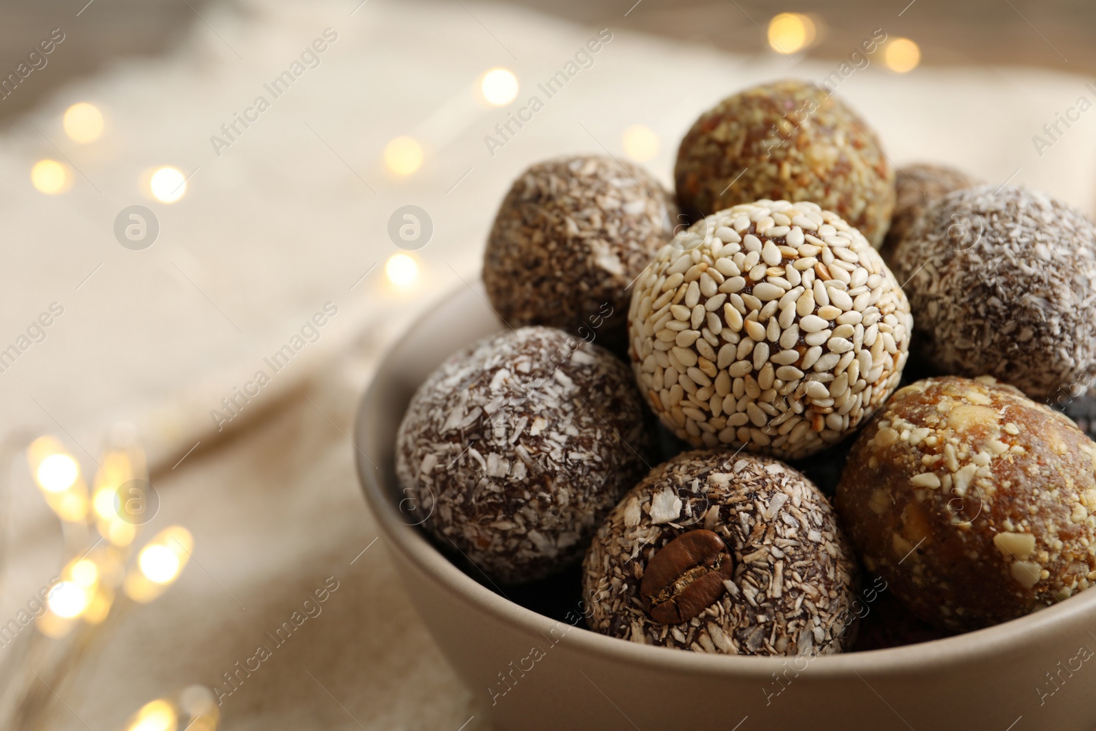 Photo of Different delicious vegan candy balls in bowl, closeup. Space for text