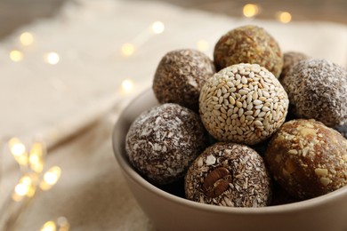 Photo of Different delicious vegan candy balls in bowl, closeup. Space for text