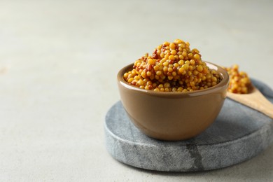 Photo of Fresh whole grain mustard in bowl on white table. Space for text