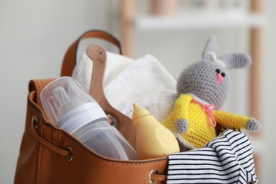 Photo of Mother's bag with baby's stuff indoors, closeup