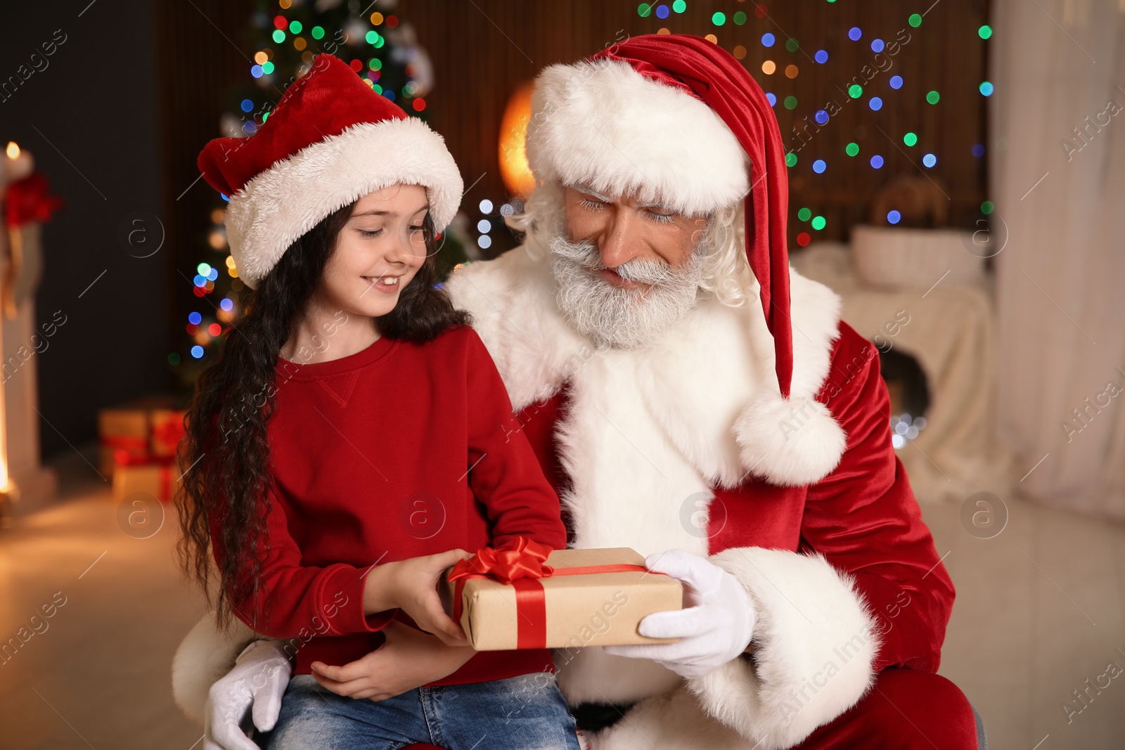 Photo of Little child with Santa Claus and Christmas gift at home