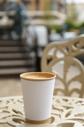 Photo of Paper cup of coffee on table outdoors. Takeaway drink