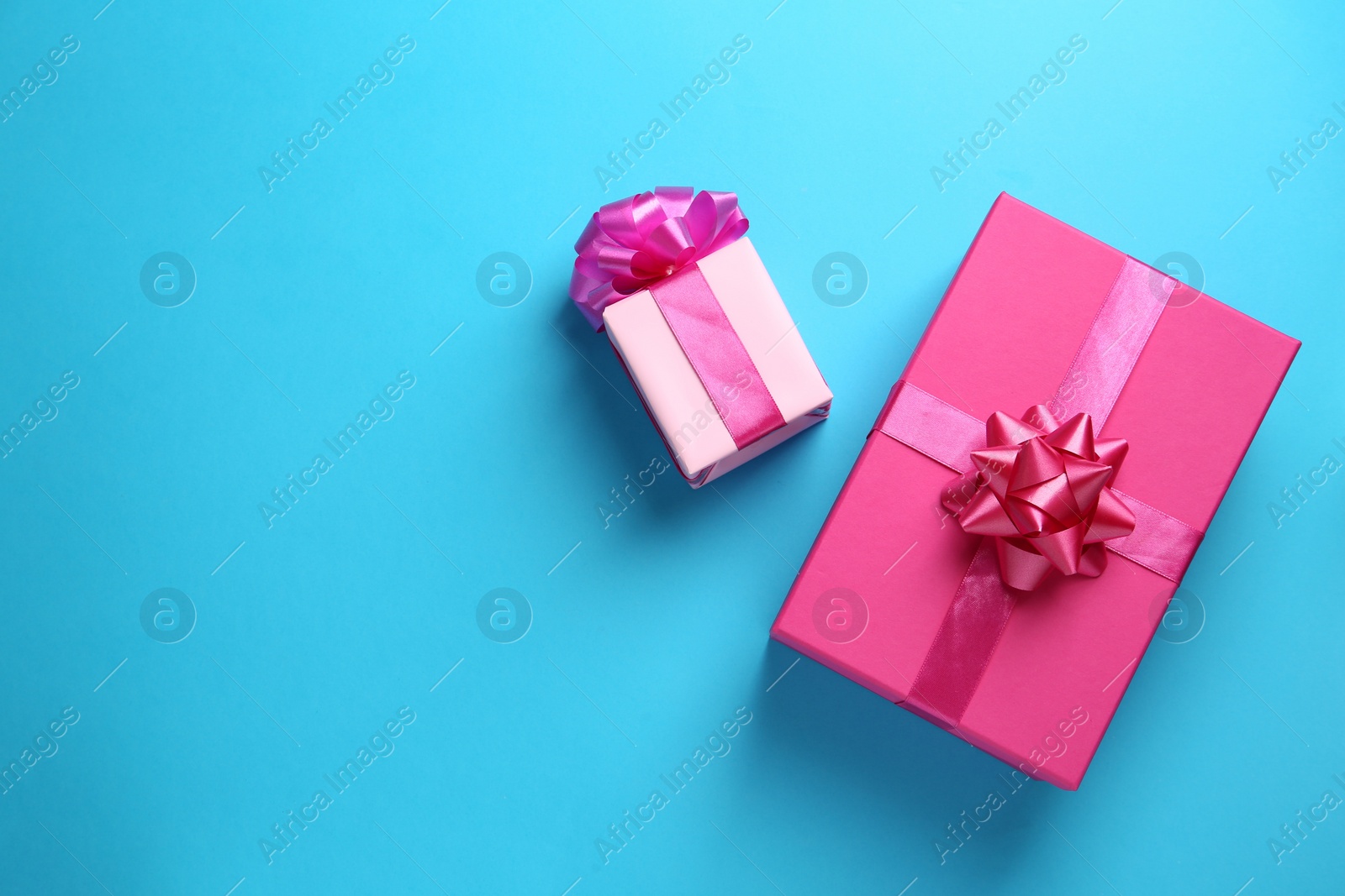 Photo of Pink gift boxes on light blue background, flat lay. Space for text