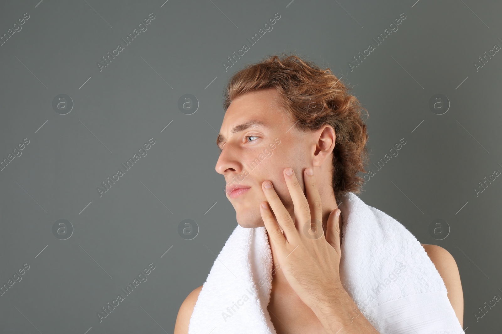 Photo of Young man touching his soft skin after shaving on gray background