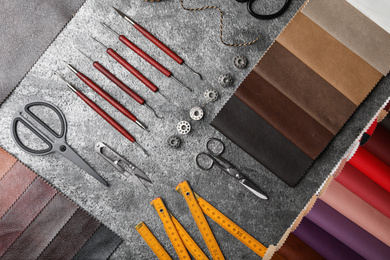 Photo of Flat lay composition with leather samples and craftsman tools on grey stone background