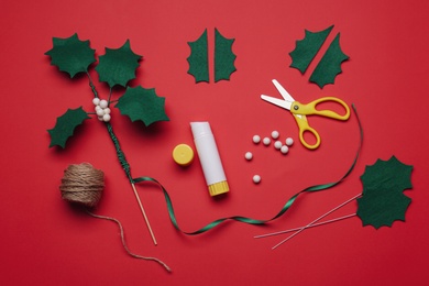 Set of instruments and materials for making mistletoe branch on red background, flat lay