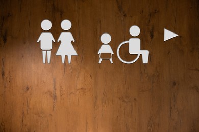 Image of White public toilet sign with arrow showing direction on wooden wall
