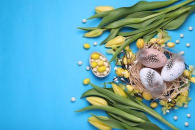 Flat lay composition with beautiful flowers and eggs on light blue background, space for text. Easter celebration