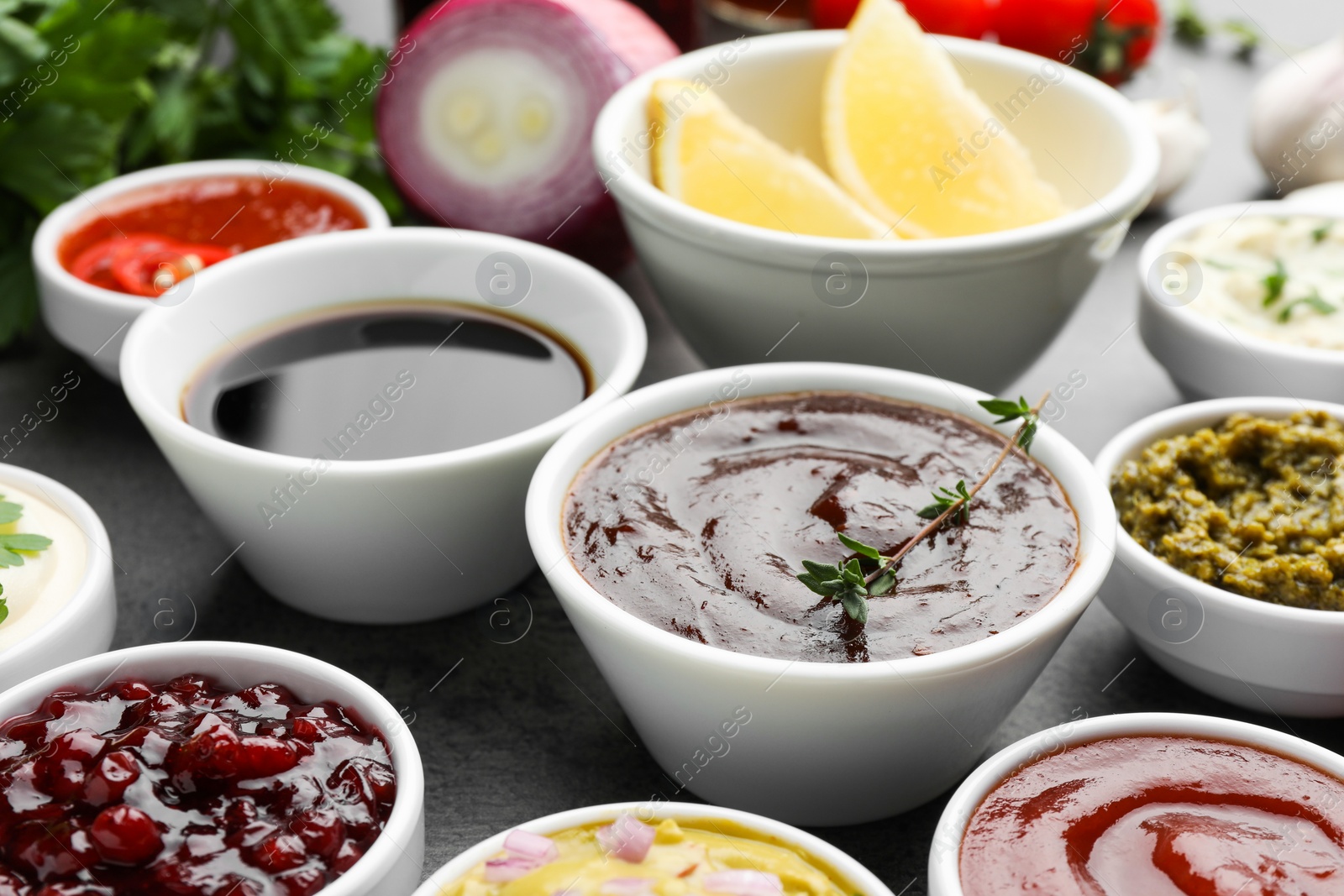 Photo of Different tasty sauces in bowls on grey table, closeup