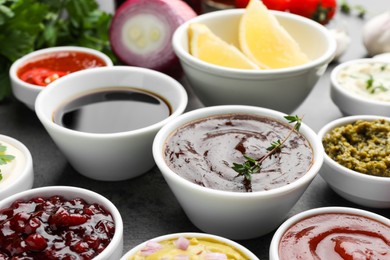 Photo of Different tasty sauces in bowls on grey table, closeup