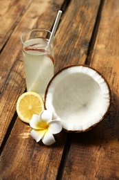 Photo of Composition with glass of coconut water and lemon on wooden table