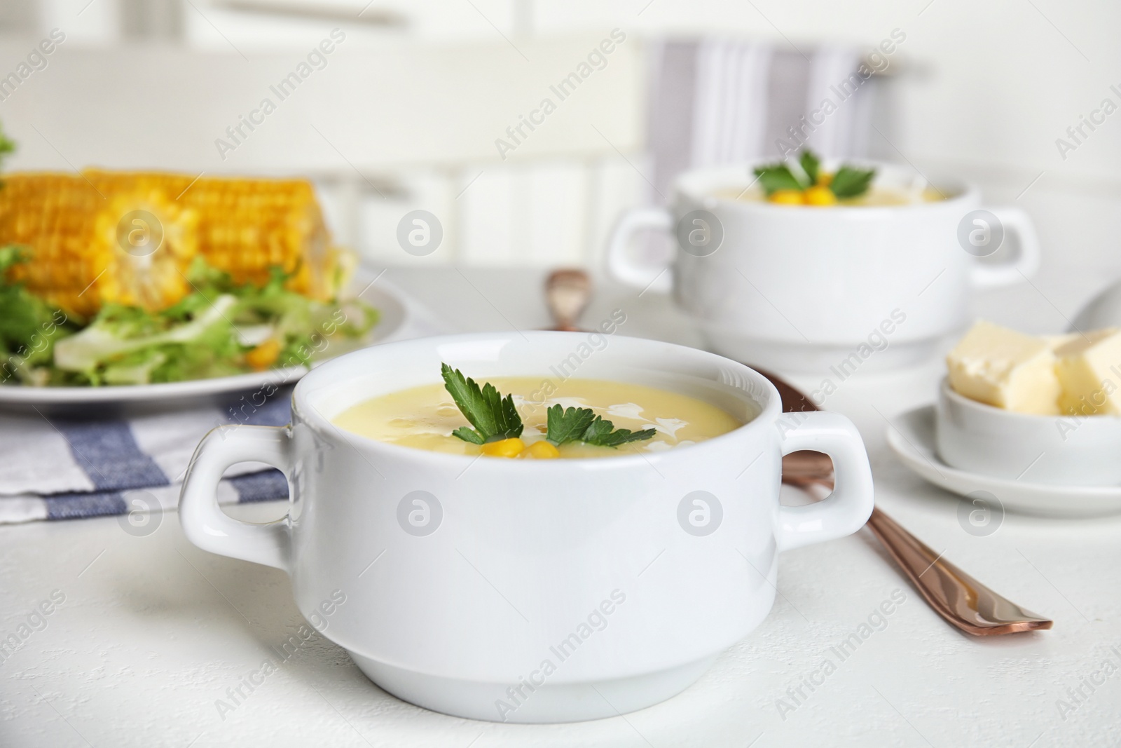 Photo of Delicious corn cream soup served on white table indoors