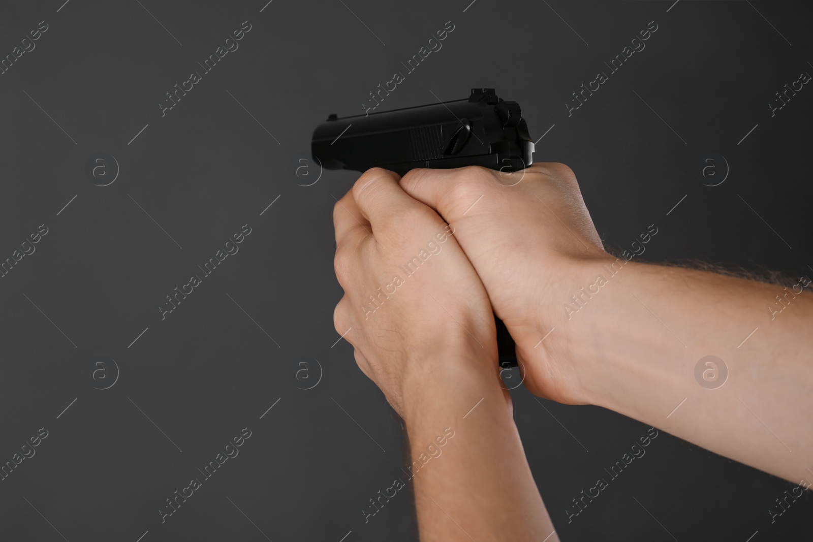 Photo of Man aiming gun on dark background, closeup
