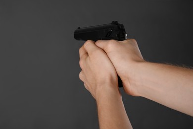 Man aiming gun on dark background, closeup