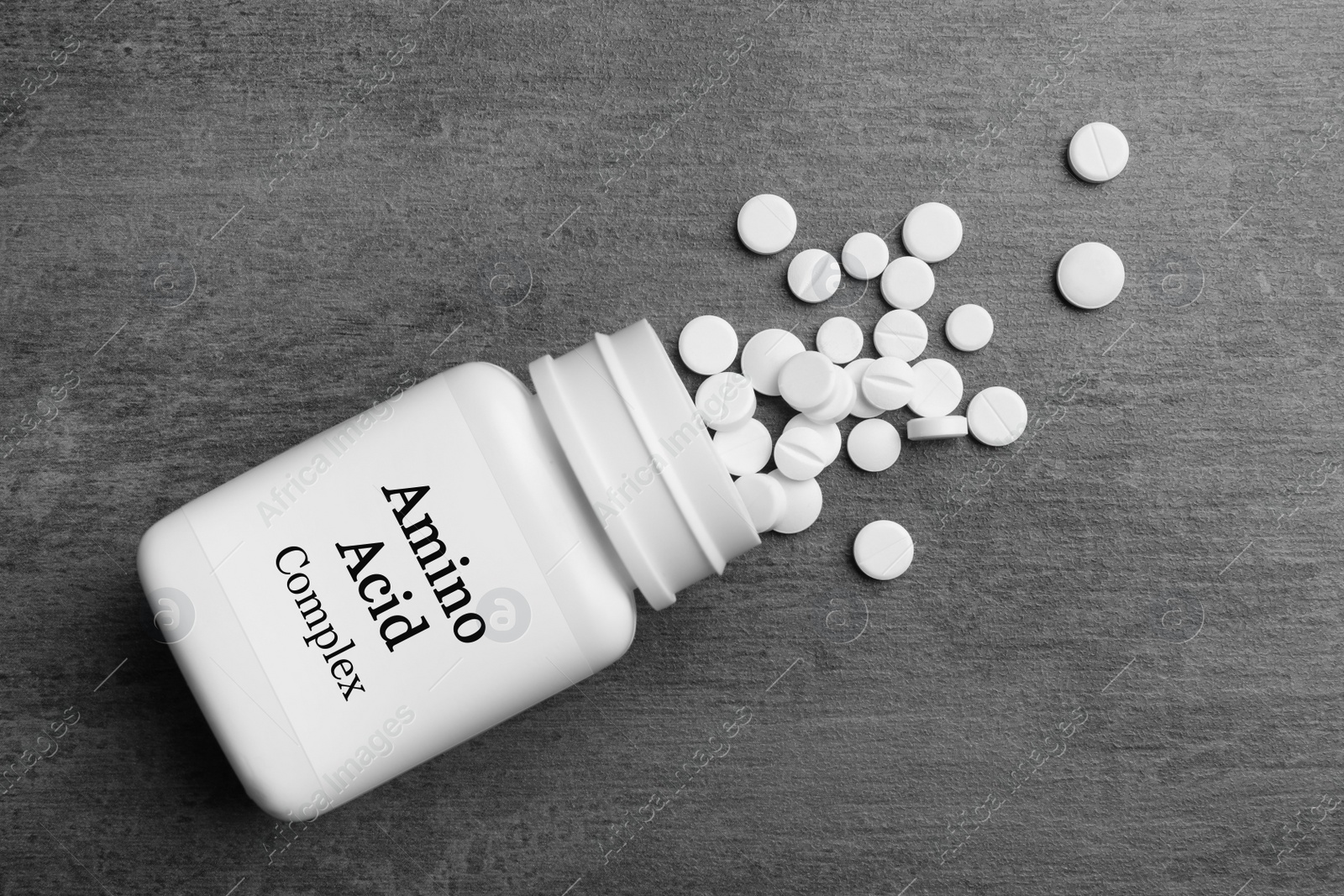 Image of Plastic bottle with Amino Acid Complex and pills on grey background, flat lay