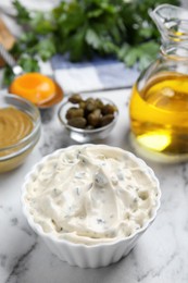 Photo of Tasty tartar sauce and ingredients on white marble table