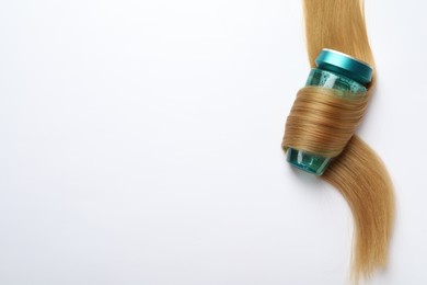 Bottle wrapped in lock of hair on white background, top view with space for text. Natural cosmetic product