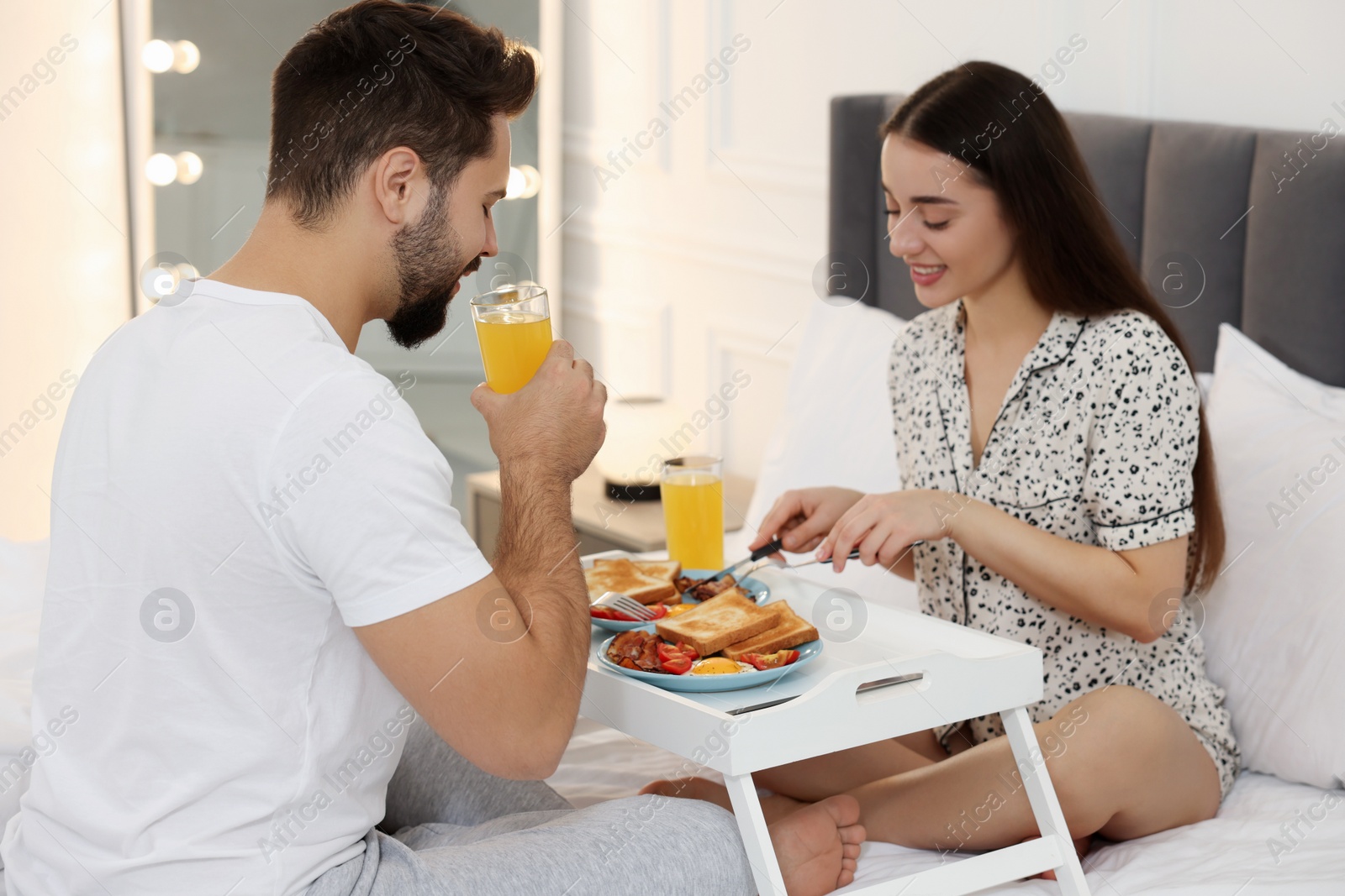 Photo of Happy couple having breakfast on bed at home