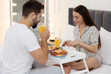 Happy couple having breakfast on bed at home